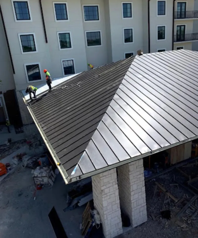 Crew installing standing seam metal roof panels on a commercial project in Rochester